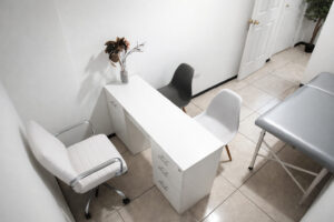 Detalle de consultorio médico en Puebla con escritorio, sillas para pacientes y camilla terapéutica